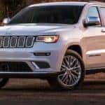 A white 2020 jeep Grand Cherokee is parked on a dirt trail near Costa Mesa, CA, at dusk.