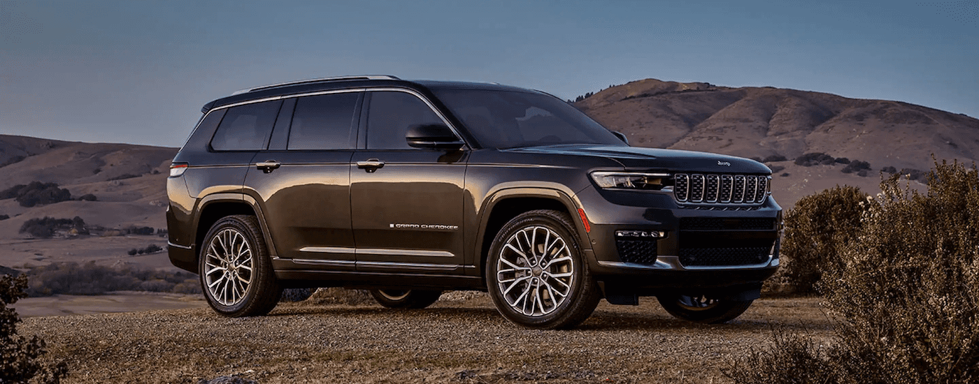 A dark grey 2023 Jeep Grand Cherokee is shown parked in a clearing.