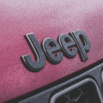 A close up of a black Jeep logo on a red Grand Cherokee is shown.