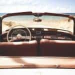 A classic convertible car is parked on a beach facing the ocean near Costa Mesa, CA.