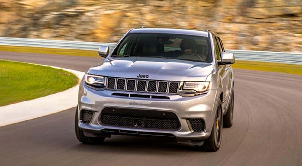 A silver 2020 Jeep Grand Cherokee is driving on a racetrack.