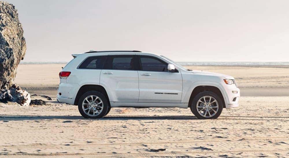 A white Jeep Grand Cherokee is shown from the side on the beach in Costa Mesa, CA.