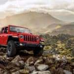 A red 2020 Jeep Wrangler iss off-roading in the mountains.