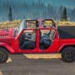 A red 2020 Jeep Gladiator Rubicon with no top or doors is shown from the side on a dirt trail, find one at your local Jeep dealership.