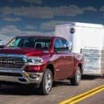 A red 2020 Ram 1500 is towing a white enclosed trailer in the desert.