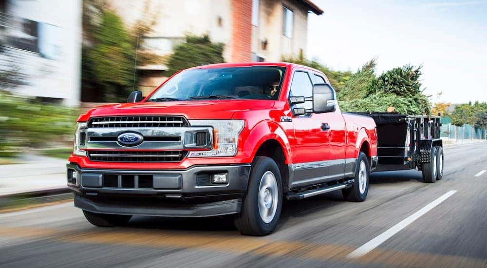 A red 2018 Ford f-150 is towing a garden trailer past apartment buildings near Costa Mesa, CA.