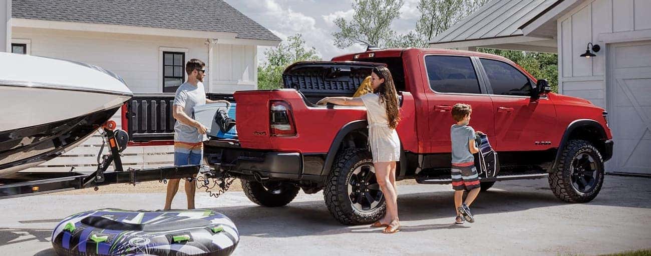 A family is loading up beach gear into the bed of a red 2020 Ram 1500.