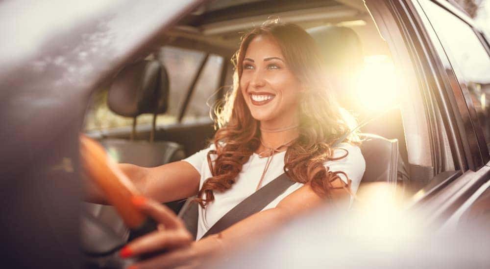 A woman is test driving a car from a used car dealer in Costa Mesa, CA, with the sun shining through the back window.