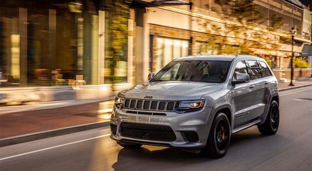 A silver 2020 Jeep Grand Cherokee is driving on a Costa Mesa street.