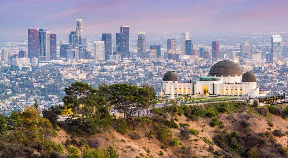The Griffith Observatory is shown on a hill overlooking the city of Los Angeles, CA.