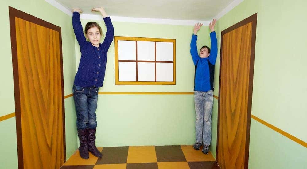 Two children are in a room to give the illusion that they can touch the ceiling.