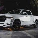 A popular Ram truck for sale in Costa Mesa, CA, a white 2020 Ram 1500 Laramie, is parked under decorative arches at night.