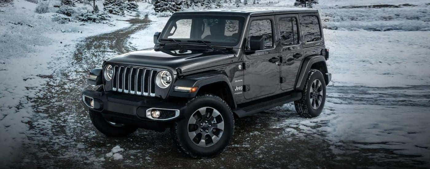 A grey 2022 Jeep Wrangler is shown from the side parked in the snowy mountains.