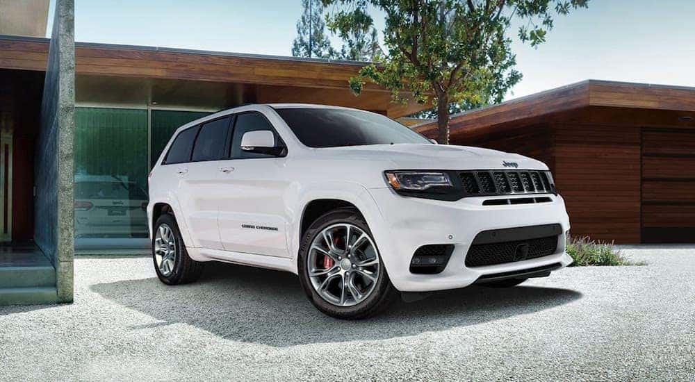 One of the popular Jeep SUVs, a white 2020 Jeep Grand Cherokee, is parked in front of a modern wooden home in Costa Mesa, CA.