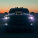 The silhouette of a 2021 Ram 1500 TRX is shown from the front with the headlights on.