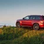 A red 2020 Jeep Grand Cherokee is parked on a cliff overlooking the ocean near Costa Mesa, CA.