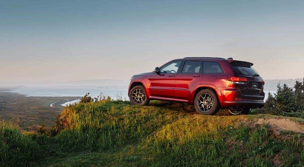 A red 2020 Jeep Grand Cherokee is parked on a cliff overlooking the ocean near Costa Mesa, CA.