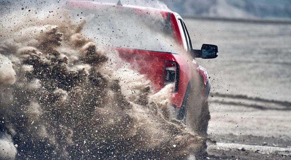 One of the new Ram trucks, a red 2021 Ram 1500 TRX, is shown from the rear kicking up sand near Costa Mesa, CA.