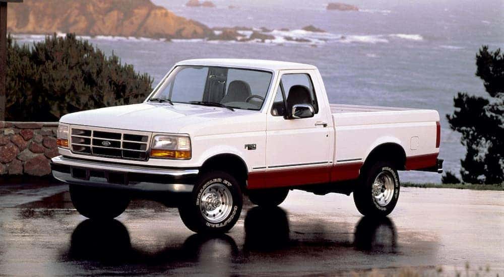 A white 1996 used Ford F-150 is parked on wet pavement with the ocean in the background.