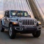 A silver 2020 Jeep Wrangler Saraha Unlimited is driving over a modern cable bridge after leaving a Jeep dealership near you.