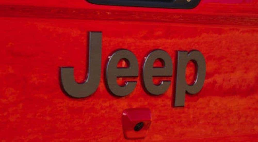 A dark grey Jeep logo is shown on a red Jeep SUV.
