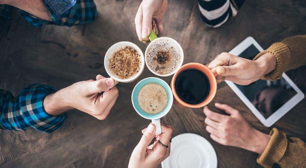 A top down view of 4 friends touching coffee mugs at a coffee shop in Los Angeles, CA.