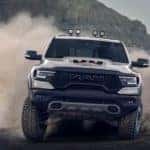 A silver 2021 Ram 1500 TRX is off roading in the desert kicking up dust.