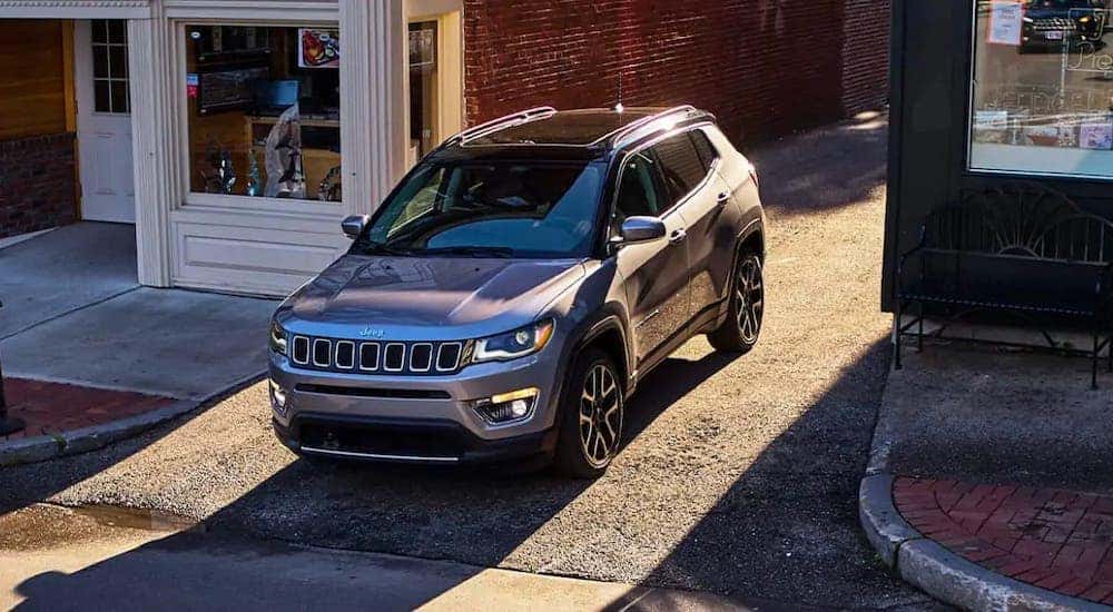 A gray 2021 Jeep Compass is pulling out of an alley.
