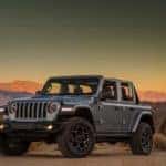 A silver 2021 Jeep Wrangler Unlimited 4xe is parked between rock formations at dusk.