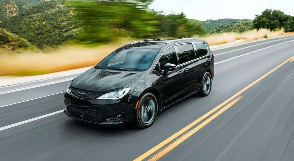 A black 2020 Chrysler Pacifica is driving on a highway after leaving a used car dealer in Orange County.