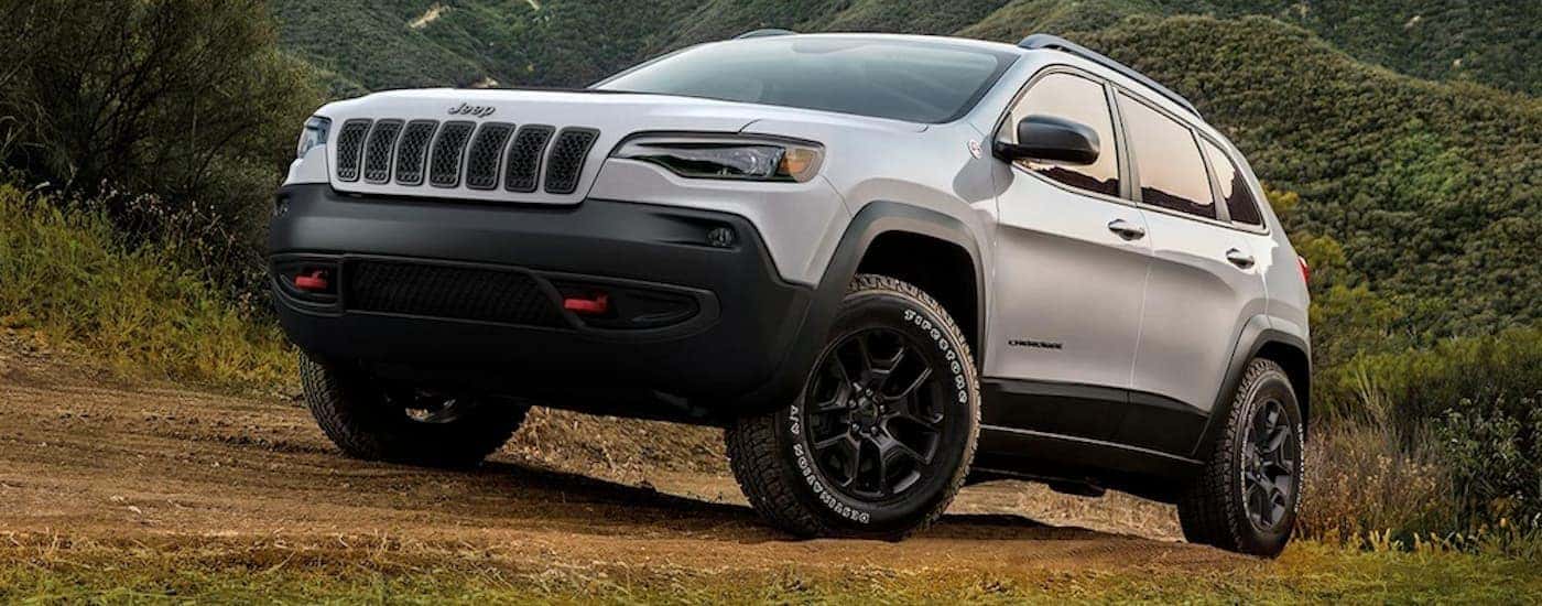 A white 2019 used Jeep Cherokee is off-roading up a dirt trail.