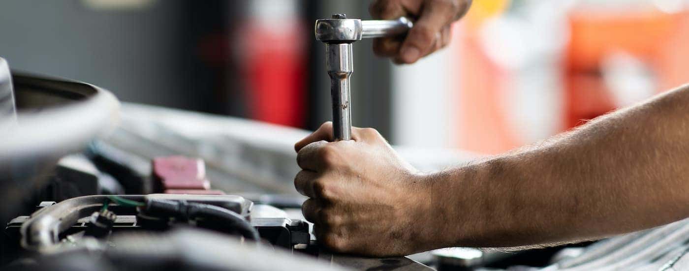 A person is performing maintenance on a used Jeep Cherokee.