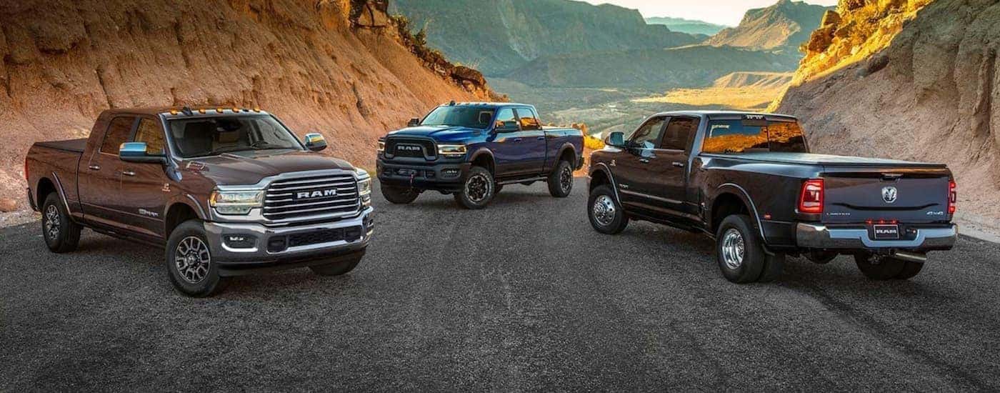 A brown, a blue, and a black 2019 used Ram 2500 are parked across a road with desert mountain views.