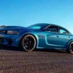 A blue 2021 Dodge Charger is driving on a desert highway after leaving a California Dodge dealer.