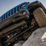 A blue 2021 Jeep Wrangler Rubicon 392 is shown climbing a rock from a low angle.