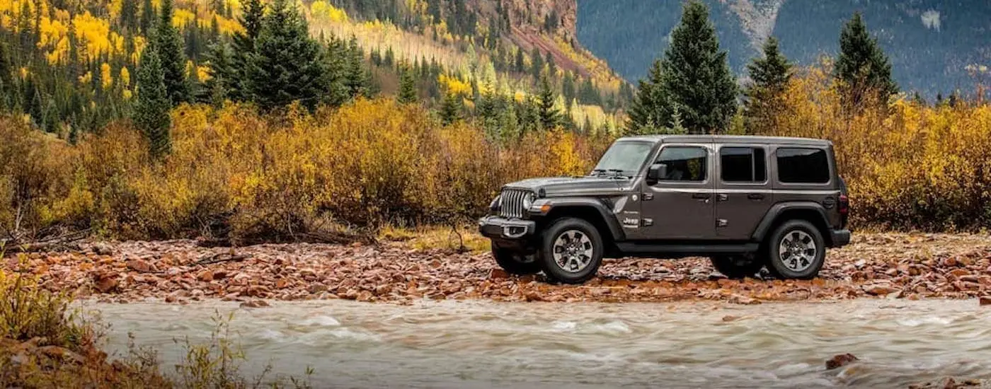 A grey 2018 Jeep Wrangler Unlimited is shown from the side parked next to a river.