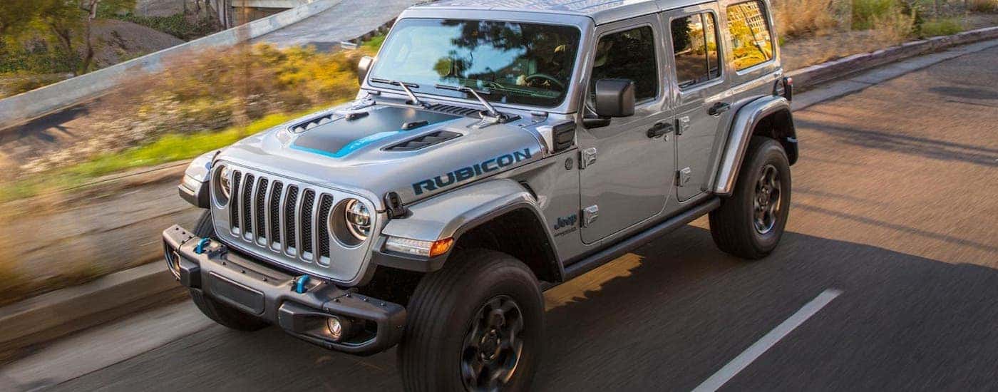 A silver 20221 Jeep Wrangler 4xe is driving on a city street.