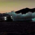 A gray 2021 Ram TRX is driving through sand dunes kicking up dust after leaving a Ram TRX dealer.