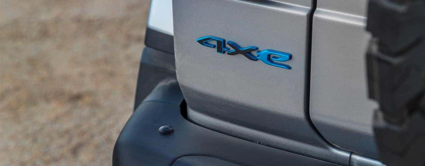 A close up shows the blue 4xe emblem on a gray 2021 Jeep Wrangler 4xe.