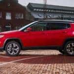 A red 2021 Jeep Compass is shown from the side parked on a brick pathway.