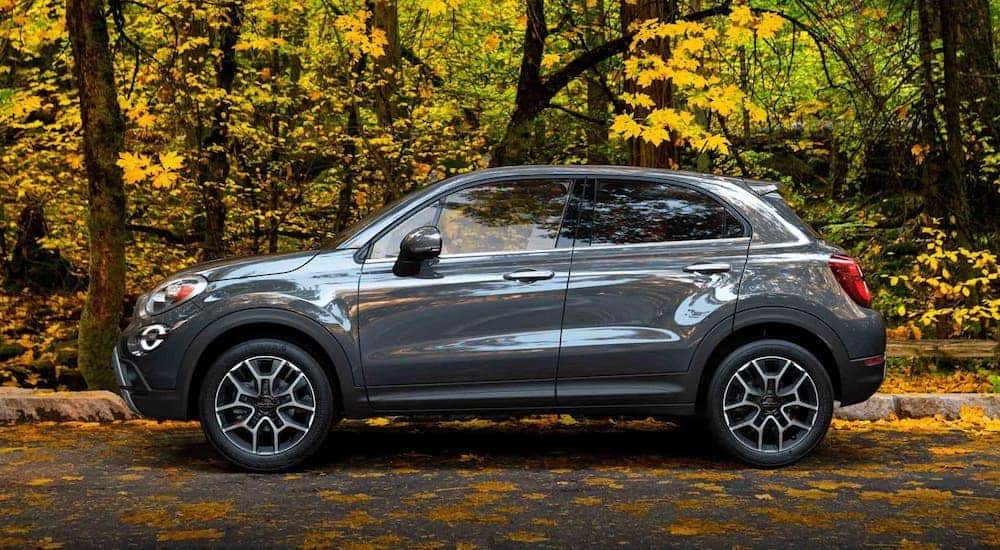 A gray 2020 Fiat 500x is shown from the side parked in front of trees.