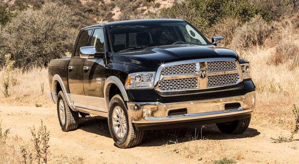 A black 2017 Ram 1500 is driving on a dirt trail.