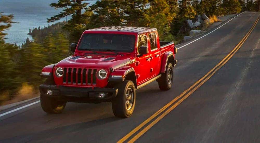 A red 2020 Jeep Gladiator is driving on a highway after leaving a used pickup dealership.