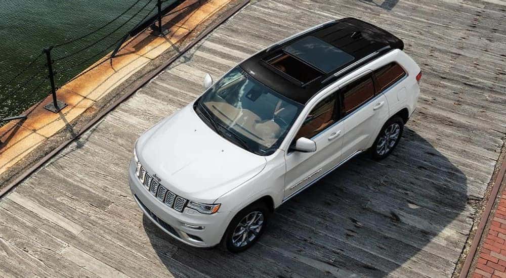 A white 2021 Jeep Grand Cherokee Summit is driving on a board walk.