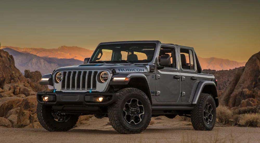 A silver 2021 Jeep Wrangler 4xe is parked in the desert at sunset after reviewing the Jeep Wrangler buyers guide.