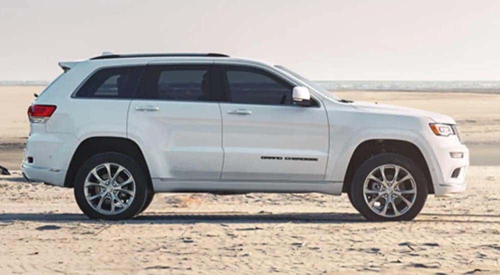 A white 2020 Jeep Grand Cherokee is shown from the side on a beach.