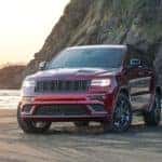 A dark red 2020 Jeep Grand Cherokee is parked on an ocean beach after leaving a used Jeep dealership In Southern California.