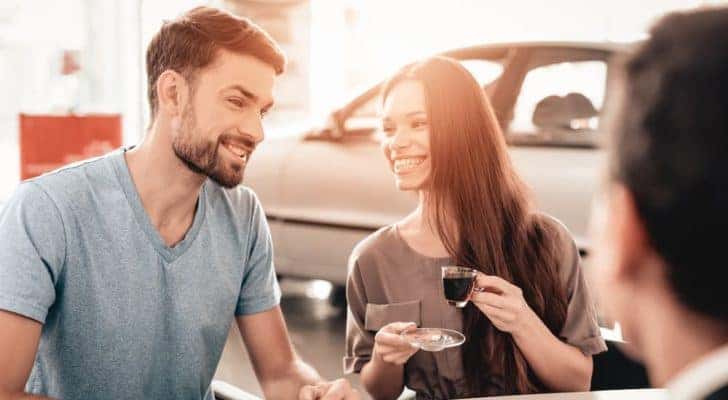 A couple is talking to a salesperson at a used Jeep dealership in Southern California.