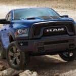 A blue 2019 Ram 1500 Classic is off-roading in an open dirt area after leaving a used Ram dealership in Southern California.
