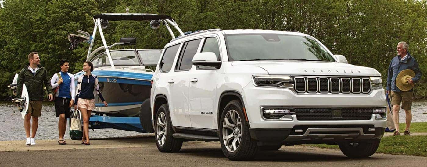 A white 2022 Wagoneer is shown from the front towing a boat.